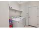 Functional laundry room with washer, dryer, shelving, and a convenient exterior access door at 45734 W Sky Ln, Maricopa, AZ 85139