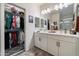 Bathroom featuring double sinks, white cabinets, a large mirror, and a well-organized walk-in closet at 5140 E Desert Forest Trl, Cave Creek, AZ 85331
