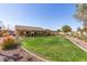 Expansive backyard featuring a well-maintained lawn, desert landscaping, and a covered patio area at 8554 W Keim Dr, Glendale, AZ 85305