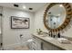 Modern bathroom with a large round mirror, marble countertops, and decorative artwork at 11268 E Moonlight Cyn, Scottsdale, AZ 85255