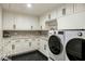 Bright laundry room with modern washer and dryer, marble countertops, and ample cabinet storage at 11268 E Moonlight Cyn, Scottsdale, AZ 85255