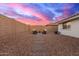 Spacious backyard features desert landscaping, patio and outdoor furniture with sunset sky at 11430 E Neville Ave, Mesa, AZ 85209