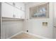 Bright laundry room featuring ample white cabinet storage, a wooden shelf, and natural light from the window at 12222 S Appaloosa Dr, Phoenix, AZ 85044