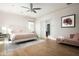 Relaxing bedroom featuring hardwood floors, a ceiling fan, and a sliding door to the ensuite bathroom at 20299 N 102Nd Pl, Scottsdale, AZ 85255