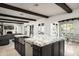 Kitchen island with marble countertop, stainless steel sink, dark cabinets, and wood beam ceiling at 20299 N 102Nd Pl, Scottsdale, AZ 85255