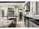 Open kitchen featuring stainless steel appliances, white cabinets, black countertops, and an island with a sink at 20299 N 102Nd Pl, Scottsdale, AZ 85255