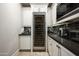 Wine room with a large wine refrigerator surrounded by custom white cabinets and a dark countertop at 20299 N 102Nd Pl, Scottsdale, AZ 85255