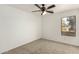 This bedroom features a ceiling fan and a bright window with neutral carpet flooring at 21397 N Goles Dr, Maricopa, AZ 85138