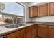 A bright kitchen featuring wood cabinets, granite countertops, a stainless steel sink, and a large window at 21397 N Goles Dr, Maricopa, AZ 85138