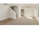 Bright living room with neutral carpet and white walls, featuring a staircase and archway at 21397 N Goles Dr, Maricopa, AZ 85138