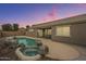 Backyard view of the house with a pool and spa against a colorful dusk sky at 22949 W Yavapai St, Buckeye, AZ 85326