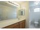 A bathroom featuring wooden cabinets, a large mirror, and a shower and tub combination at 22949 W Yavapai St, Buckeye, AZ 85326