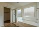 This bright bathroom features a tub, window, and glass-doored shower at 22949 W Yavapai St, Buckeye, AZ 85326