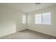 A bright bedroom with carpet, baseboards, and two windows allows plenty of natural light at 22949 W Yavapai St, Buckeye, AZ 85326