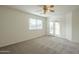 This bedroom features plush carpeting, a ceiling fan, and double doors leading to the backyard at 22949 W Yavapai St, Buckeye, AZ 85326