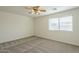 A spacious bedroom with a ceiling fan, and a large window with neutral carpet at 22949 W Yavapai St, Buckeye, AZ 85326