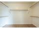 This is a walk-in closet with built-in shelving and wooden rods for hanging clothes at 22949 W Yavapai St, Buckeye, AZ 85326