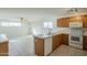 Bright kitchen with a breakfast bar, oak cabinets, white appliances, and tile flooring at 22949 W Yavapai St, Buckeye, AZ 85326