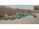 Backyard pool featuring a rock waterfall and relaxing spa area, enclosed by a tall privacy fence at 22949 W Yavapai St, Buckeye, AZ 85326