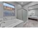 Bathroom showcases a soaking tub under window with gray trim, adjacent to a glass shower enclosure, and a bedroom at 23004 E Desert Spoon Dr, Queen Creek, AZ 85142