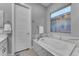 Modern bathroom with tub, tile surround, and bright window at 23004 E Desert Spoon Dr, Queen Creek, AZ 85142