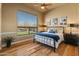 Bright bedroom featuring hardwood floors, ceiling fan, and a view of the landscaped yard at 27561 N 84Th Dr, Peoria, AZ 85383