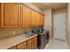 Functional laundry room with ample cabinet space, sink, modern washer, and dryer at 27561 N 84Th Dr, Peoria, AZ 85383