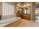 Bright bathroom featuring a soaking tub, tiled floors, and glass block window at 27561 N 84Th Dr, Peoria, AZ 85383