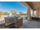 Covered outdoor kitchen with grill, with patio, fireplace and pool in background at 27561 N 84Th Dr, Peoria, AZ 85383