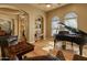 Grand piano room featuring hardwood floors, arched windows, and leather seating at 27561 N 84Th Dr, Peoria, AZ 85383