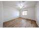 A bright, empty bedroom with a ceiling fan, wood-look floors, and a single window at 2923 E Wahalla Ln, Phoenix, AZ 85050