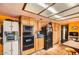 Image of a kitchen with terracotta tile, orange walls, wooden cabinetry, and black appliances at 2929 N 55Th Pl, Phoenix, AZ 85018