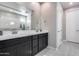 Elegant bathroom featuring dual sinks, dark cabinetry, and a large frameless mirror at 31400 N 130Th Ave, Peoria, AZ 85383