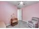 Bedroom with pink walls, ceiling fan, baby furniture, and a reclining chair at 31400 N 130Th Ave, Peoria, AZ 85383