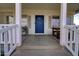 Charming front porch with seating, a blue front door, and white columns at 3929 E Flintlock Dr, Queen Creek, AZ 85142