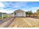 Quonset style garage with white door, adjacent paddock and white picket fence under clear blue skies at 3929 E Flintlock Dr, Queen Creek, AZ 85142