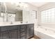 Bright bathroom with double vanity, soaking tub, tiled floors, and glass block window for natural light at 4019 W Valley View Dr, Laveen, AZ 85339