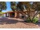 Single-story brick home featuring an attached garage, manicured landscaping, and mature trees at 4323 W Villa Theresa Dr, Glendale, AZ 85308