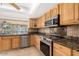 Well-equipped kitchen featuring oak cabinets, granite countertops, stainless appliances, and tile backsplash at 4323 W Villa Theresa Dr, Glendale, AZ 85308