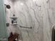 Shower featuring chrome shower head, grab bar, built in shelves and marbled walls at 4530 E Dragoon Ave, Mesa, AZ 85206