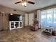 Bright living room with tile floors, a ceiling fan, a large window, and a TV with a media cabinet at 4530 E Dragoon Ave, Mesa, AZ 85206