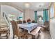 Dining room with modern chandelier, long wooden table, 8 chairs, and a large window with blue curtains at 5110 S Sandstone St, Gilbert, AZ 85298