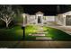 Night view of a beautifully landscaped single-story home with illuminated walkway and manicured lawn at 6325 N 83Rd Pl, Scottsdale, AZ 85250