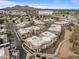 An aerial view of tan condo buildings surrounded by landscaping and near shopping, Mummy Mountain, and Paradise Valley at 7601 E Indian Bend Rd # 1017, Scottsdale, AZ 85250