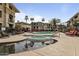 Beautiful community pool with rock water feature, palm trees, lounge chairs, and nearby condo buildings at 7601 E Indian Bend Rd # 1017, Scottsdale, AZ 85250