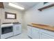 Functional laundry room with a modern washer and dryer, wood countertop, ample cabinet space, and patterned tile floor at 837 E Divot Dr, Tempe, AZ 85283