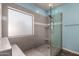 Bathroom featuring a glass-enclosed shower with bench and tiled walls at 8850 W Laurel Ln, Peoria, AZ 85345