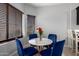 Cozy dining area with a modern table, four blue chairs, and a window with blinds at 8850 W Laurel Ln, Peoria, AZ 85345