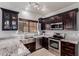 Well-equipped kitchen with stainless steel appliances, dark wood cabinets, and granite countertops at 8850 W Laurel Ln, Peoria, AZ 85345