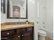 Bathroom with brown vanity, granite countertop, decorative mirror, and a shower-tub combo at 891 W Palo Brea Dr, Litchfield Park, AZ 85340